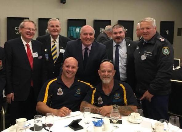 NSW Police RSL sub-Branch Padre, Father Paul O'Donoghue; President Mervyn Morgan; State Minister for Veterans' Affairs, David Elliott; Tony King, President, Police Association of NSW; and Acting Police commissioner Gary Worboys, stand behind two Invictus Games competitors, Peter Arbuckle and